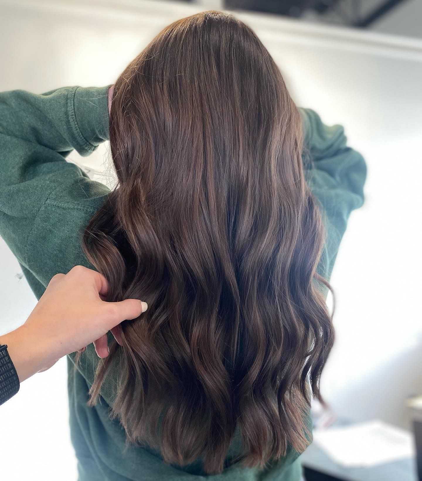 Person showcasing their long, wavy brown hair.